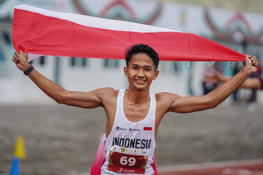 Pelari Indonesia Yad Hafizudin berlari mengibarkan bendera Merah Putih usai memenangkan lomba lari kategori pria 1.500 meter U 20 pada event kejuaraan Atletik Asia Tenggara U-18 & U-20 di Stadion Madya Atletik Kawasan Sport Centre Sumut, Kabupaten Deliserdang, Provinsi Sumatera Utara, Sabtu (15/11/2025). Pelari asal Lombok Timur menjadi penyumbang medali emas pertama pada event ini dengan catatan waktu 3:56.94.